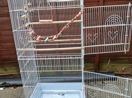 Large bird cage with toys, food containers. and perches.